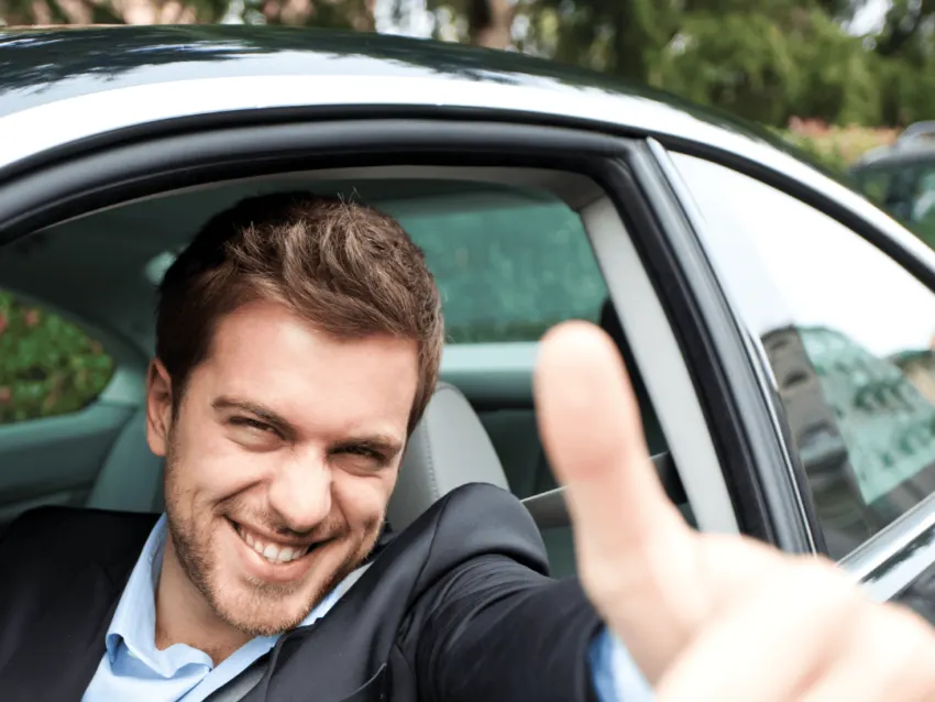 Motorista sorrindo ao volante de um carro